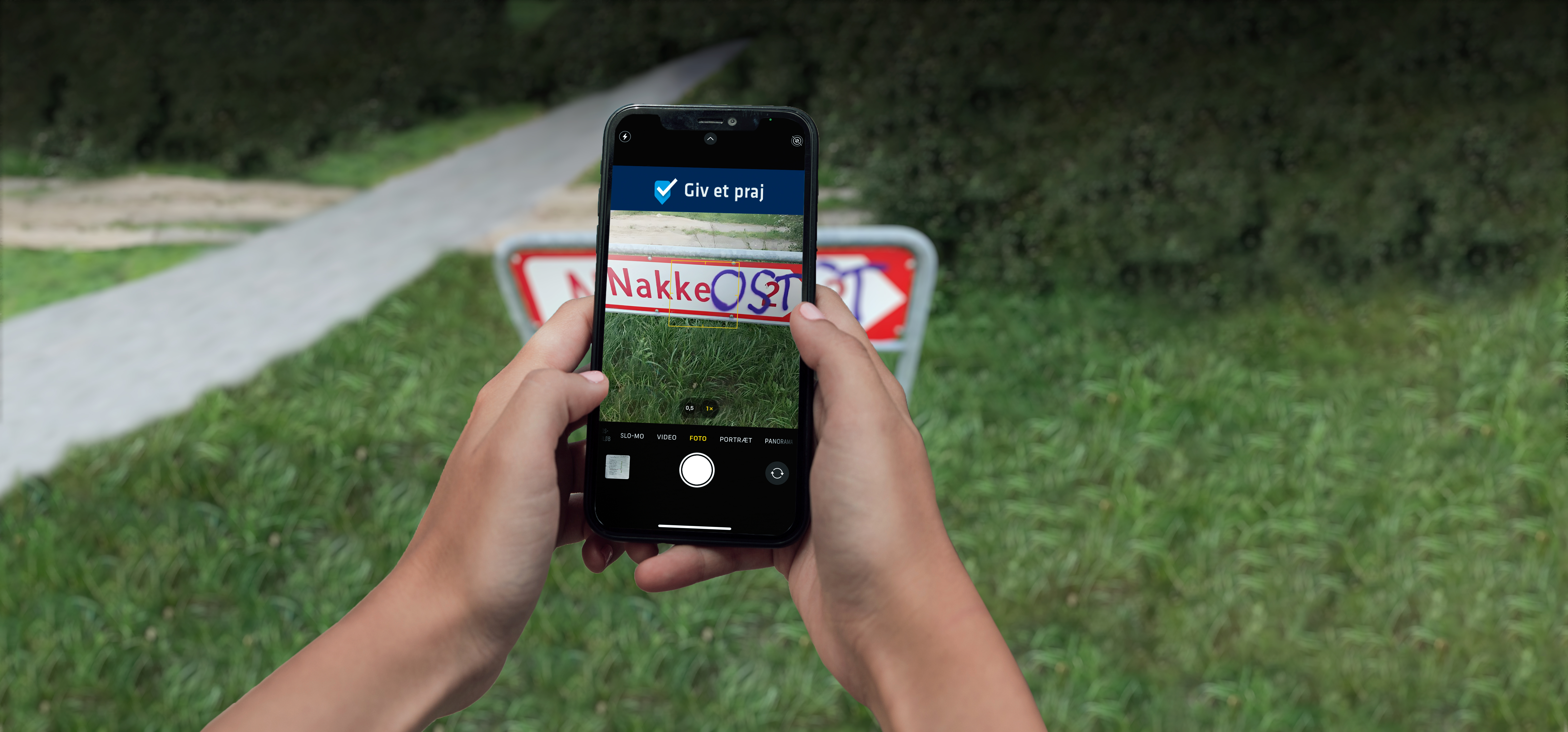 Person tager billede med sin mobil af et skilt hvor der står Nakke på. Nogle bøller har skrevet "OST" med graffiti, så det ligner, at der står "Nakkeost".